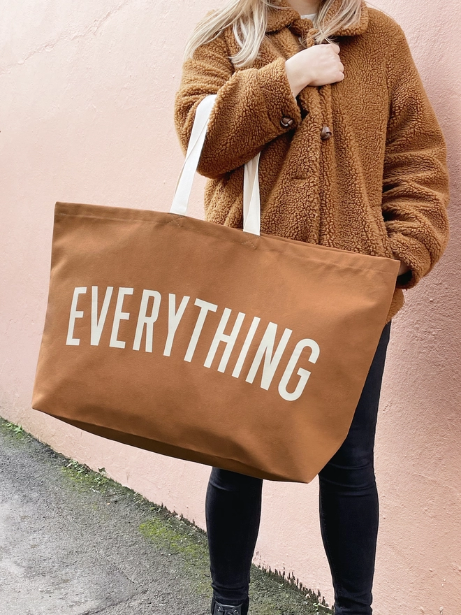Model holding the Everything oversized tote bag in tan