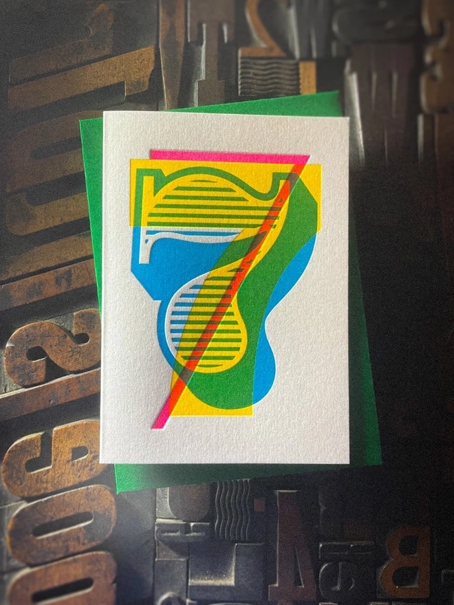 Handmade letterpress 7th birthday card featuring bold overlapping numerals printed in vibrant fluorescent cyan, magenta and yellow inks. Each card is individually hand printed using traditional letterpress techniques on luxury paper stock, creating a beautifully tactile finish with a deep impression and rich layered colours inspired by the CMYK printing process. Printed on a traditional letterpress from 1915. A wonderful artisan printed birthday card.