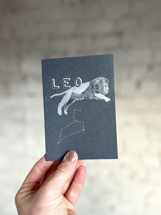 : a greetings card featuring a greyscale illustration of a zodiac style lion with the text “LEO”