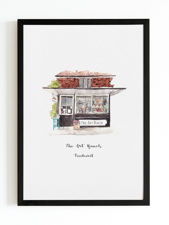Beautiful watercolour illustration of The Art Bunch florist shop in Ticehurst.  A black and white fronted building with plants outside and in through the large window. The watercolour style is painted with a black pen outline and organic loose style with small details.  The print is on white background with black frame around.