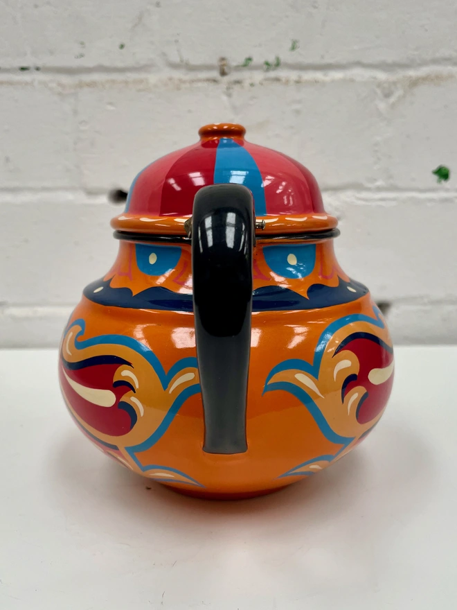 Orange vintage teapot with hinged lid, hand painted with a traditional fairground inspired design in pink, red, yellow and blue.