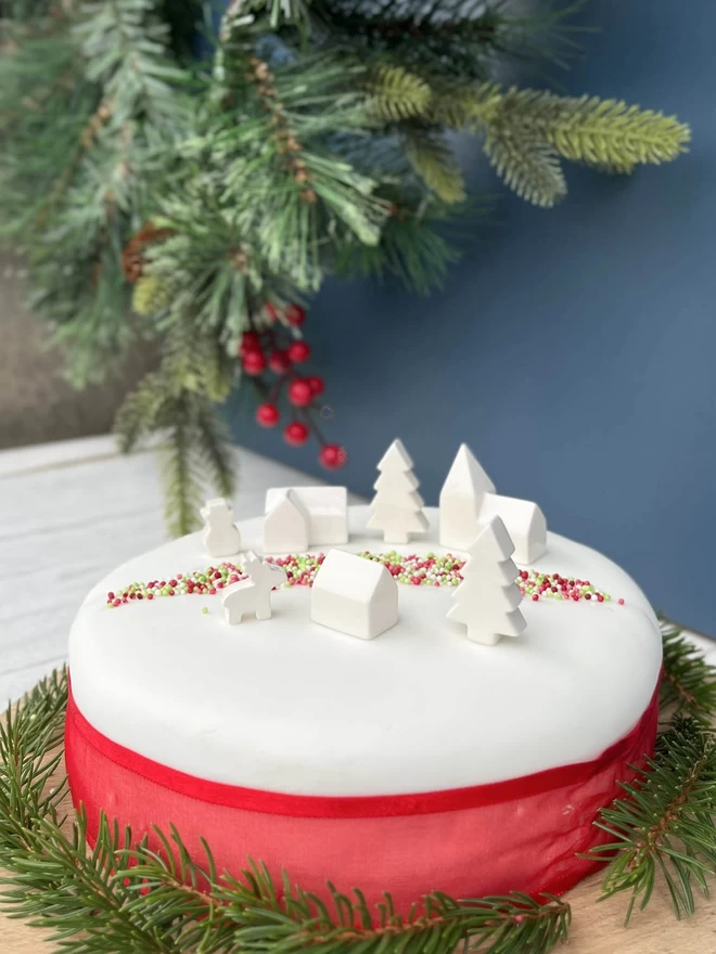 Handmade ceramic Mini Christmas Village used as a cake decoration. 