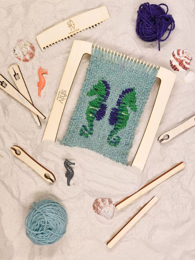 seaside weaving kit. a green weave piece with green seahorses photographed on a loom.