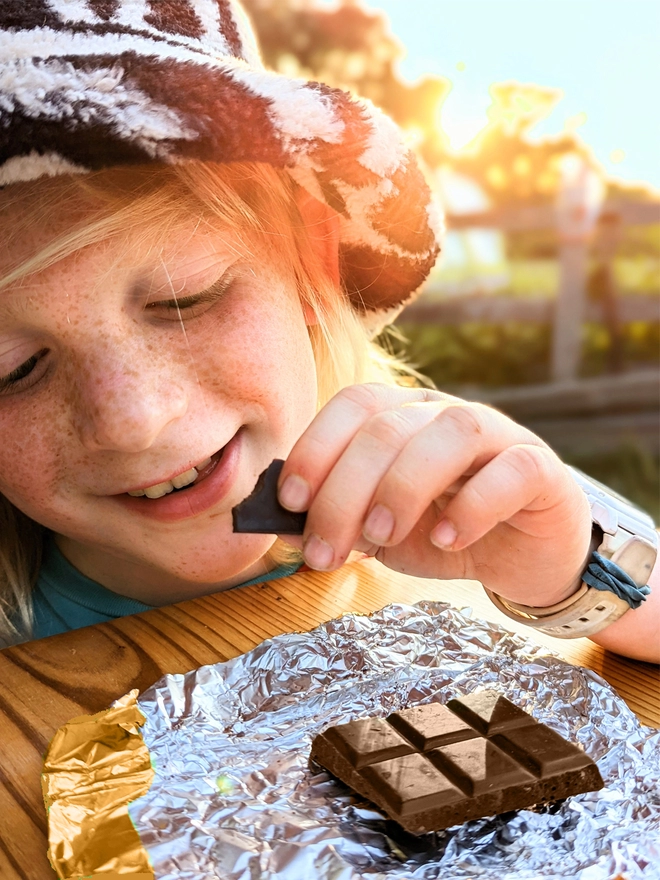 Happy young child opening gold foil wrapped charity milk chcoclate with cheesecake gingernut crunch