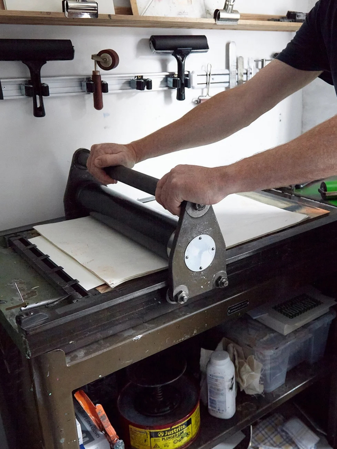 you are the one linocut. a linocut phrase being printed in a manual press.