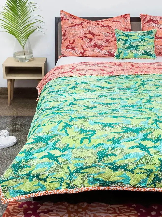 Big Cat Camo Quilt, a pink and green quilt on a bed in a bedroom. 