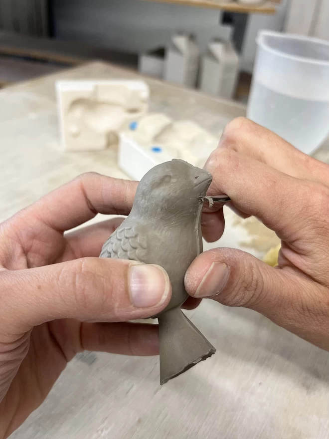 Katie is tiding the seams of a freshly cast clay bird handle.