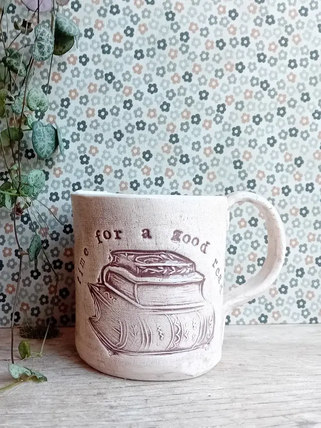 'time for a good read' earthenware mug. a cream mug linocut with a book and slogan on the front. 