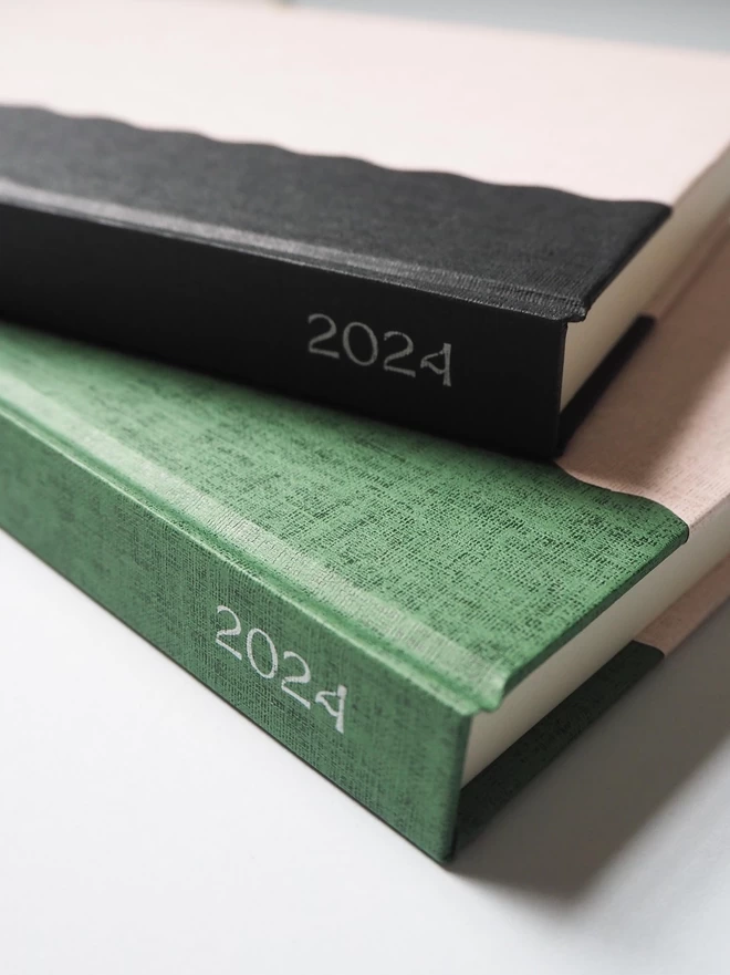 two notebooks stacked up with 2024 written on the spine