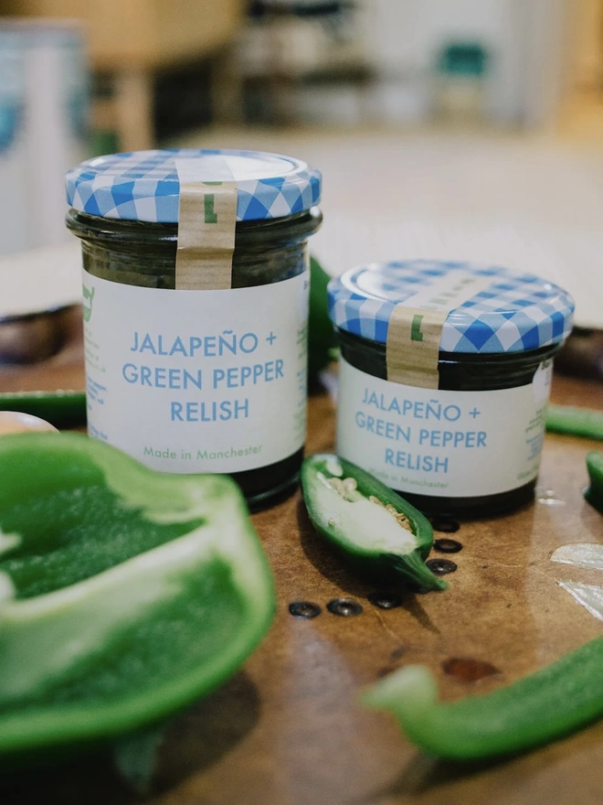 Jar Of Jalapeño & Green Pepper Relish, set of jars of relish on a tray next to jalapeños. 