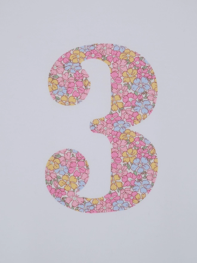 a white birthday t-shirt with a number 3 cut from liberty floral print on the front