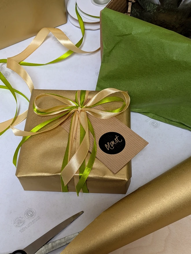 Giftwrapped box from BLOMST, gold recycled paper with gold and green satin bow