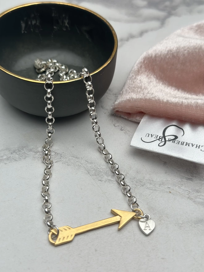 sterling silver chain with gold horizontal feather charm. a small silver heart charm hangs from the chain next to the feather