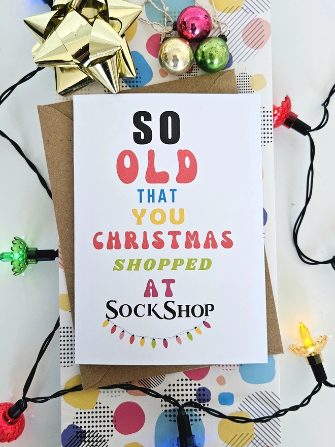 A photograph of the front of a humorous A6 greeting card illustrated using brightly coloured text and the retro shop logo. The text says so old you Christmas shopped at Sock Shop
