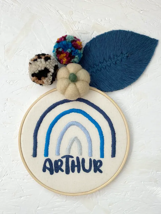 personalised name and rainbow embroidered hoop. cotton hoop embroidered with the name arthur and a rainbow in different shades of blue.