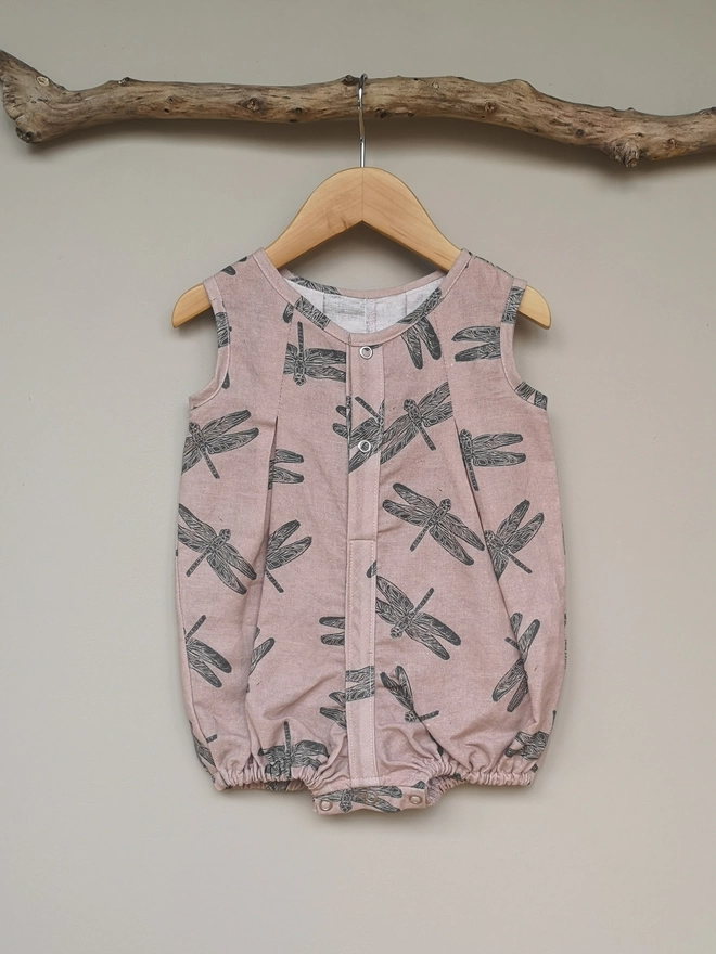 Cotton linen pink baby romper. Printed with a charcoal dragonfly. Partially opening centre front and crotch to allow for changing.