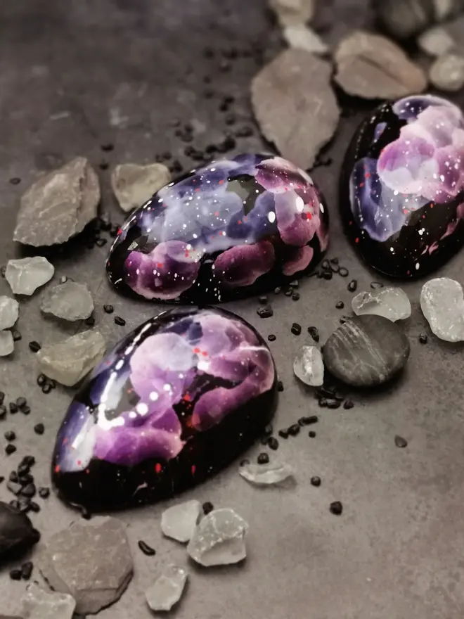 three chocolate easter egg halves, all black with purple floral decor