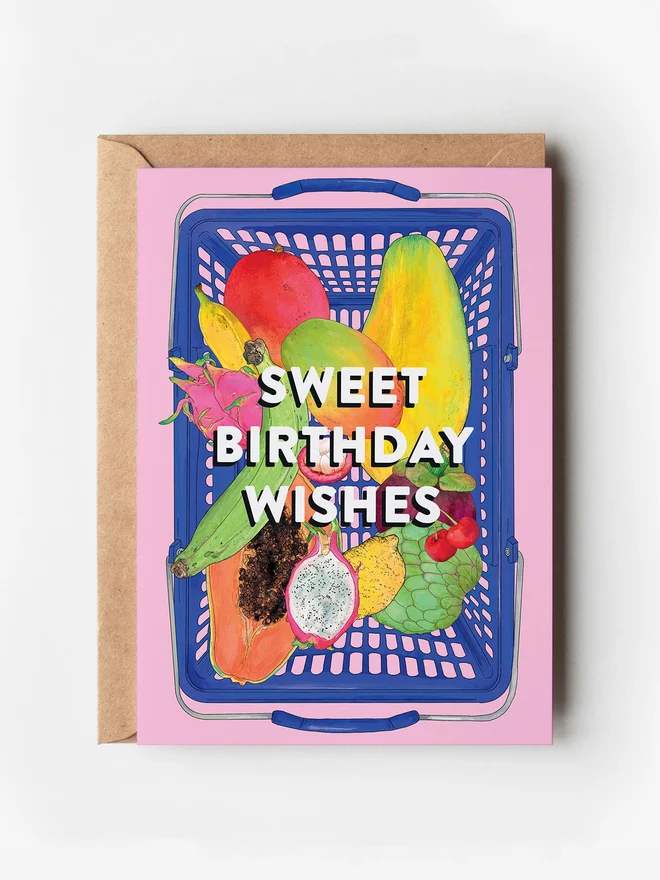 Food-inspired illustrated greeting card featuring a vibrant blue basket filled with tropical fruits, set against a bold pink background. A fun, colourful design perfect for fruit lovers and foodies alike