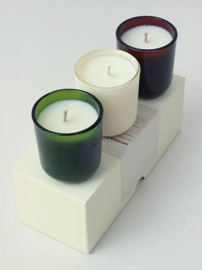 small aromatherapy soy candles (set of 3). candles arranged in row on top of box packaging.