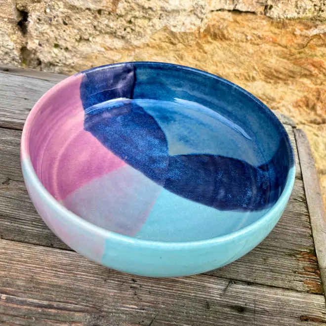 Landscape Pasta Bowl, a colourful pasta bowl on a wooden surface against a brick backdrop. 