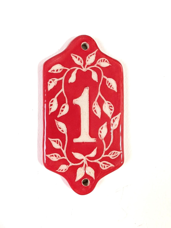 Red Sgraffito Leaf Address Tile. A tile with ‘1’.