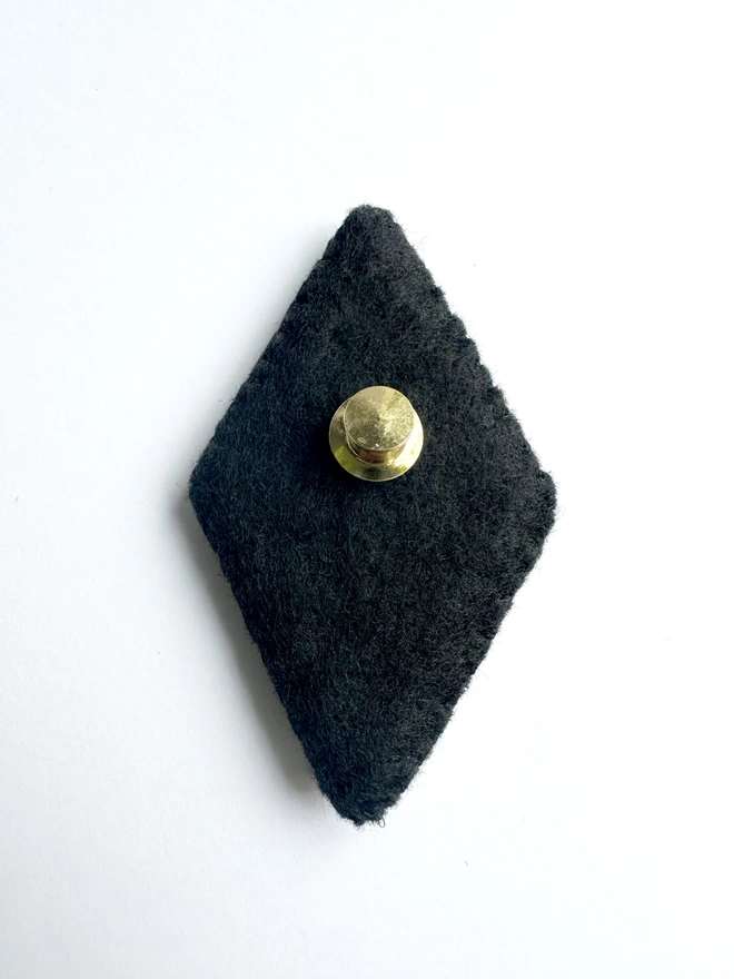 Black felt back of brooch with gold pin fastening 