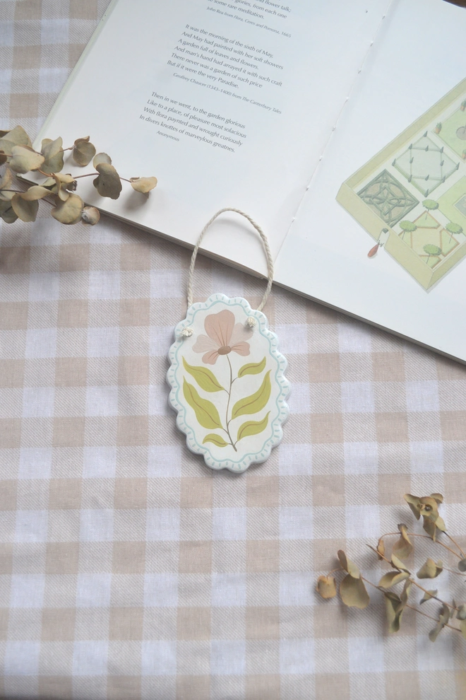 hanging ceramic ornament with blue border and pink an green flower