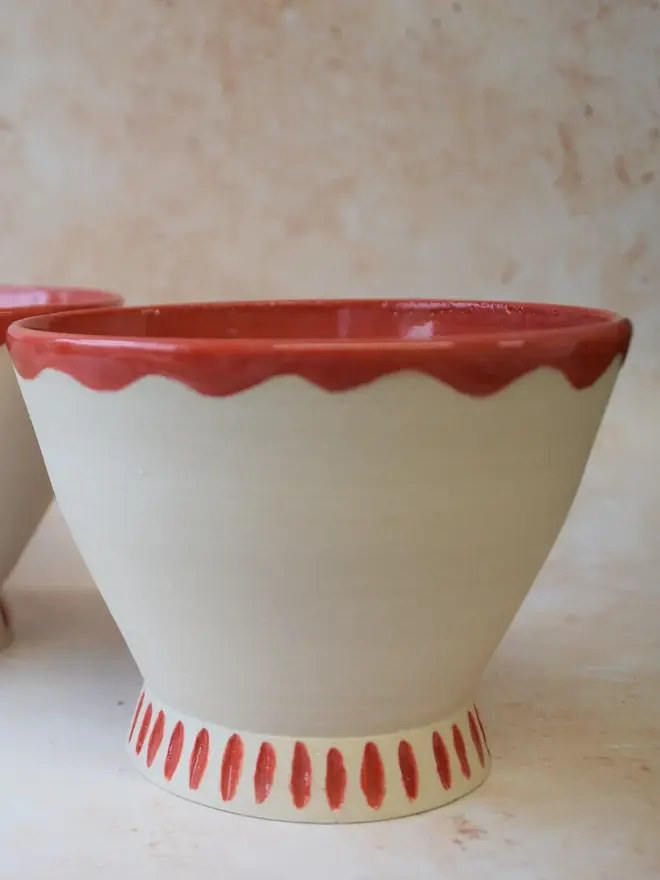 Handmade ceramic bowl — side view showing red scalloped rim and base detail