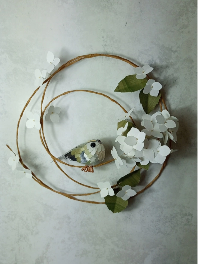 goldcrest sculpture on a white hydrangea wreath