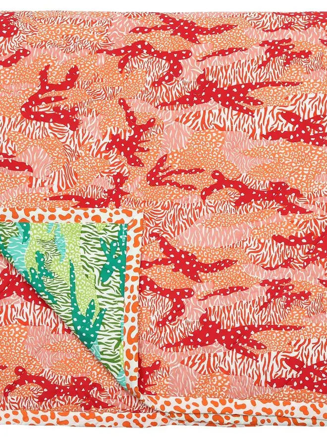 Big Cat Camo Quilt, a pink and green quilt on a bed in a bedroom. 