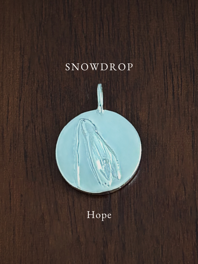 Sterling Silver Snowdrop Coin Charm on a dark background with the language of flowers meaning, hope