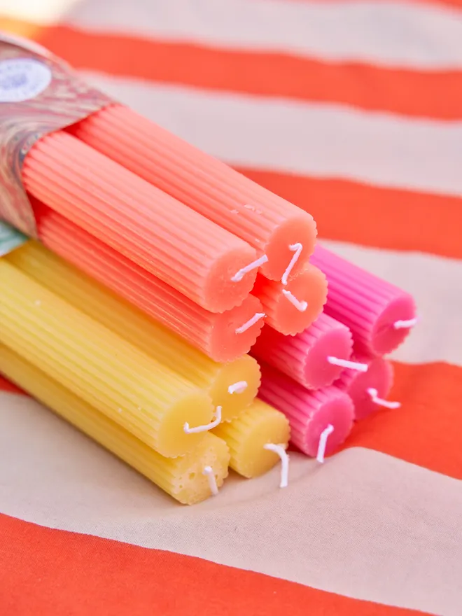 three sets of scalloped dinner candles, each with a marbled paper wrapping and ribbon