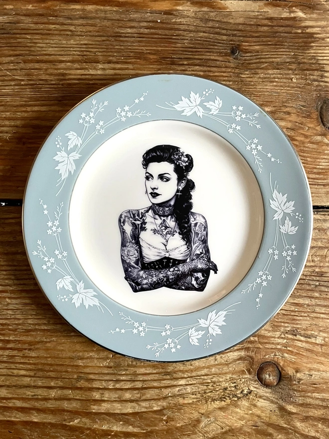 a vintage plate with ornate border, within the centre i have printed the vintage style image of a victorian tattooed sailor woman