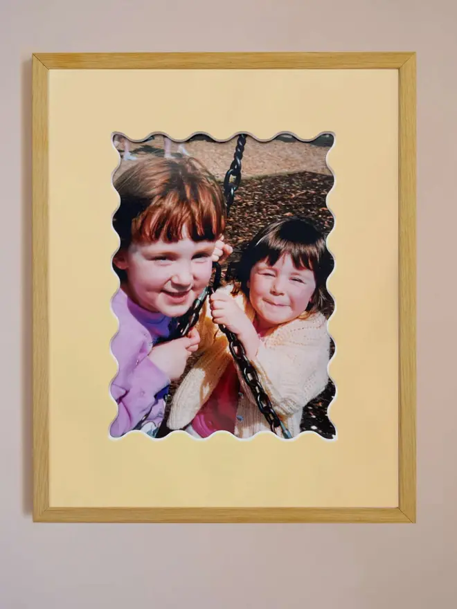 Ric rac photo mount frame with a yellow mount featuring a decorative ric rac boarder around a centered Instax photo, displayed on a neutral beige wall.