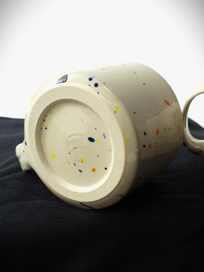 Small creamy white terrazzo cups with black, blue, and yellow splatters and glossy glaze