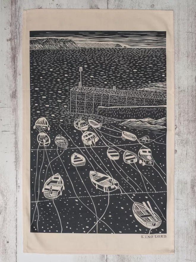 Picture of a tea towel with an image of Portscatho, taken from an original lino print