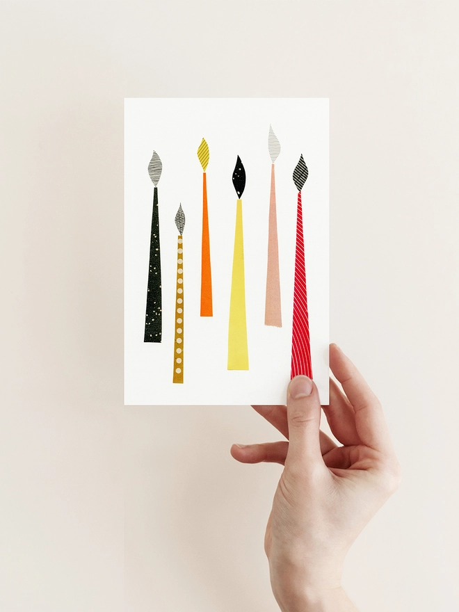 A mid century style Christmas card featuring a collection of colourful festive candles.