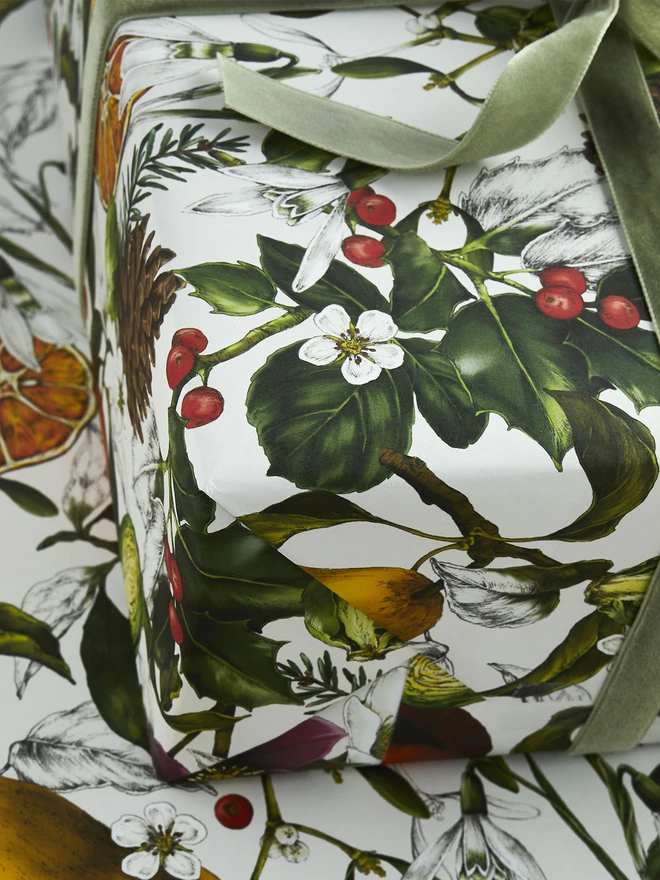 A busy ivory based christmas wrap with festive elements like clementines, holly and hellebores