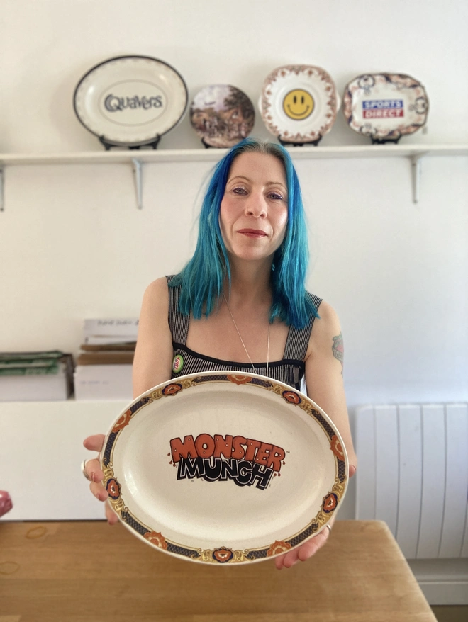 oval shaped vintage plate with the 'Monster Munch' logo in the centre. The rim of the plate is orange and dark blue, and the logo has been created to reflect these colours.
