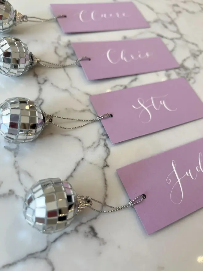 Personalised Calligraphy Wedding Lilac Place Cards, lilac place cards with a disco ball grouped together on a table. 