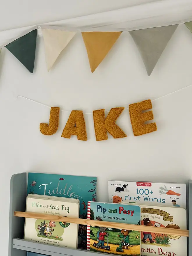 boucle letter bunting. yellow fabric bunting hung on a wall spelling 'jake'.
