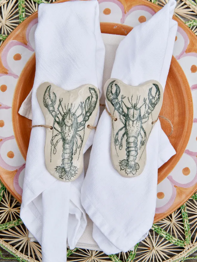 Ceramic Lobster Napkin Ring Holder, a ceramic lobster napkin sitting on a wicker placemat. 