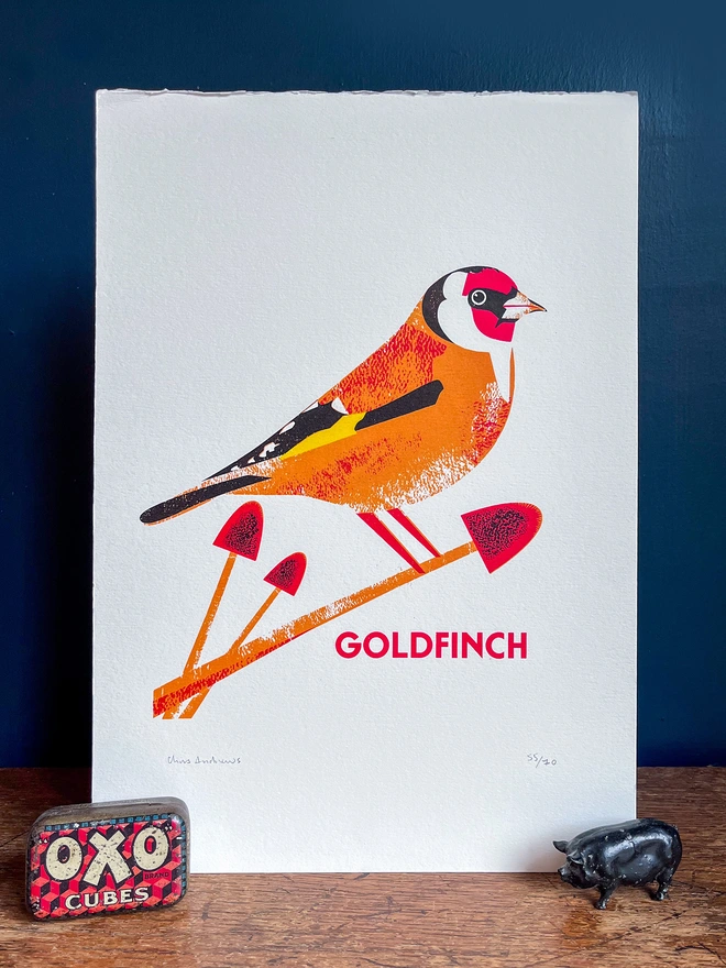 A screenprint of a Goldfinch bird on white paper against a navy blue background.