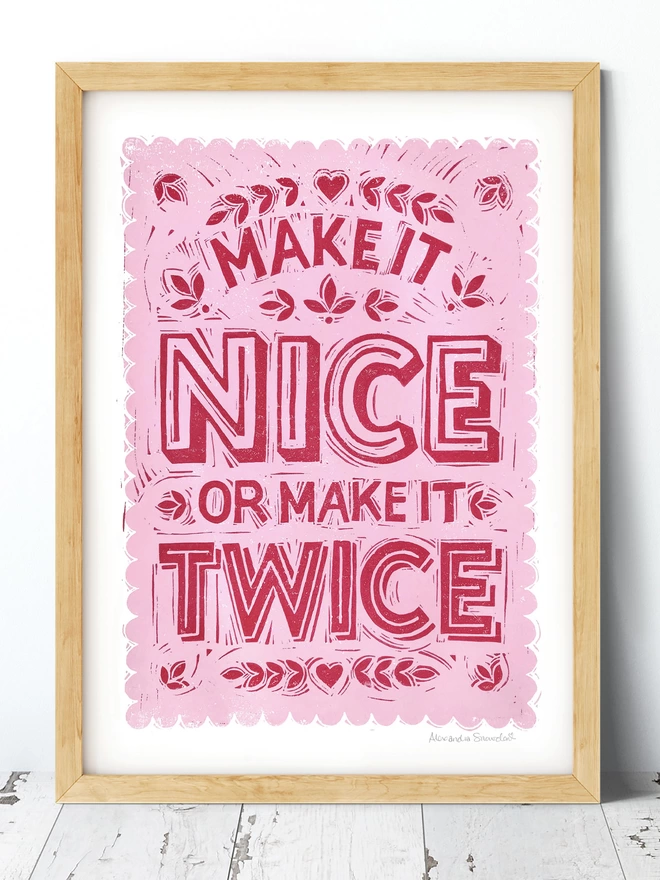 pink hand lettered make it nice or make it twice print in a wood frame