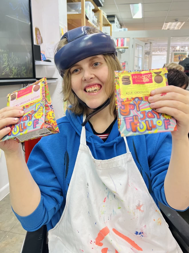 Happy artist holding colourful bag of charity full of joy milk chocolate buttons perfect for gifting