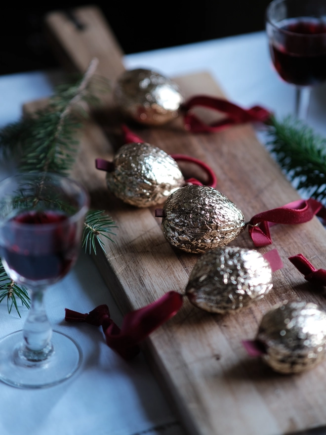 Handmade walnut Christmas ornament with delicate gold gilding, showing the natural shape and grain of the wood. A traditional, nostalgic Christmas tree decoration with timeless old-fashioned charm.