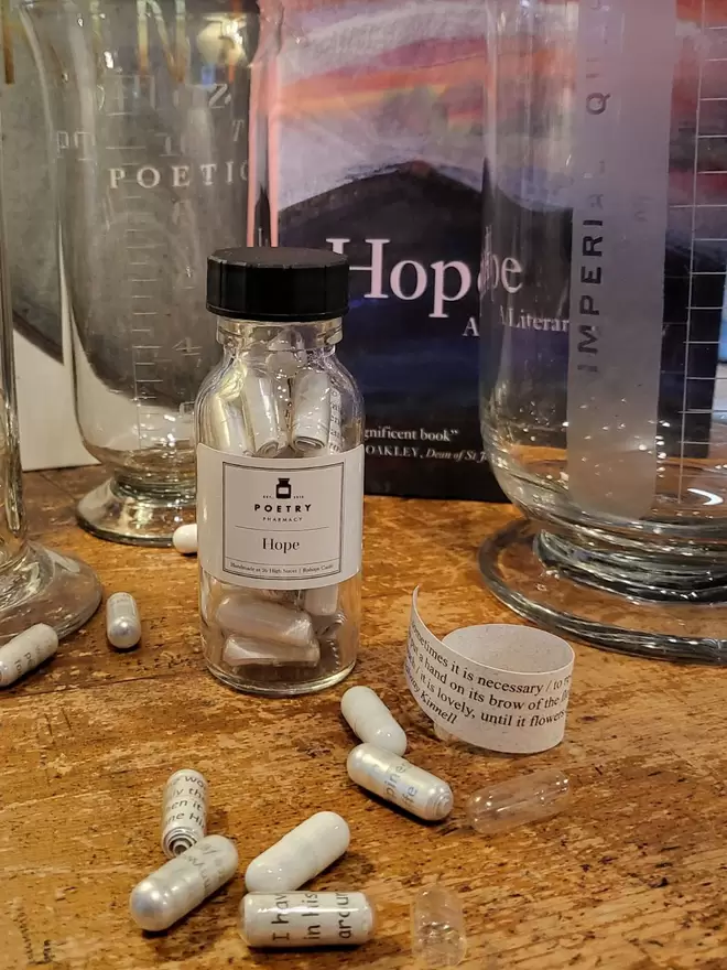 Glass bottle containing white and clear Hope poetry pills printed on banana paper