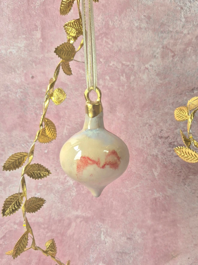 Ceramic christmas bauble decorations in a pearlescent glaze with white, cream and pink and gold, with silk ribbon and gold detailing. Photographed on a pearlescent serving dish with gold pears and christmas lights, gift, christmas, ceramics, pottery, christmas, decorations, christmas tree