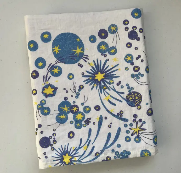 Solaris Tablecloth In White Or Blue. White tablecloth with blue and yellow starburst motifs.