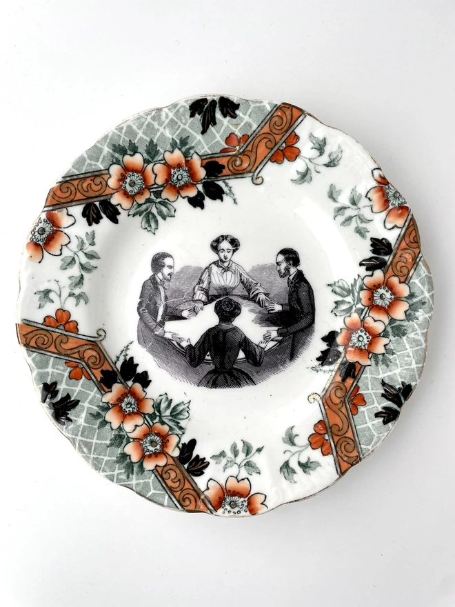 vintage plate with an ornate border, with a printed vintage illustration of a Victorian Séance in the middle 
